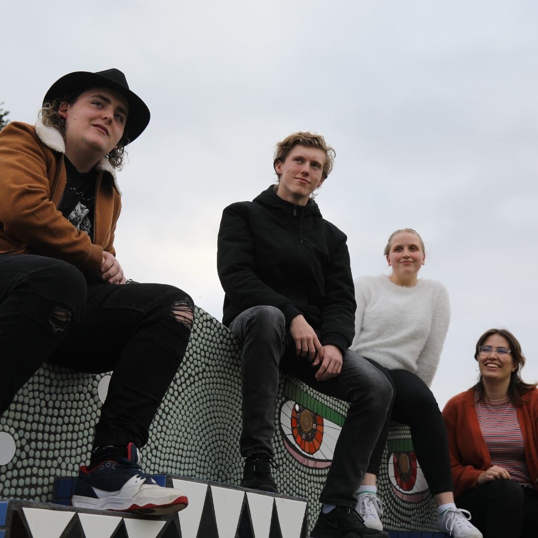 Four members of the ExpressWay Arts Crew of 2021 sit on a wall