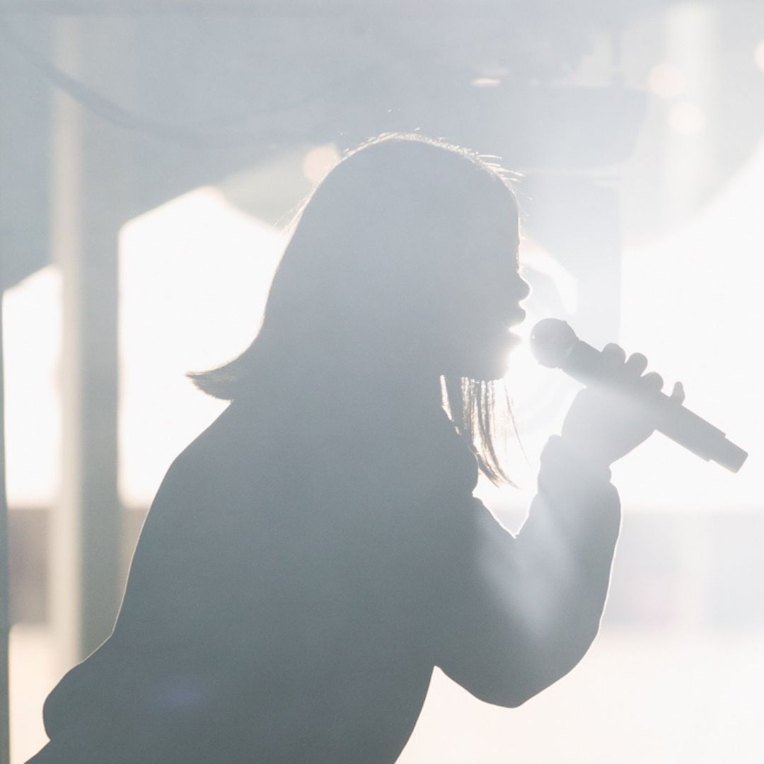 Silhouette of Elsy Wameyo singing on stage