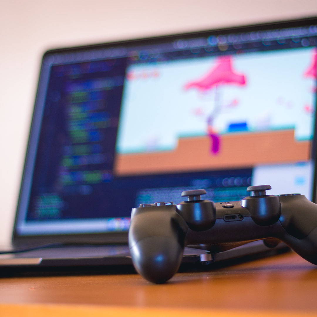 a video game controller in front of a laptop