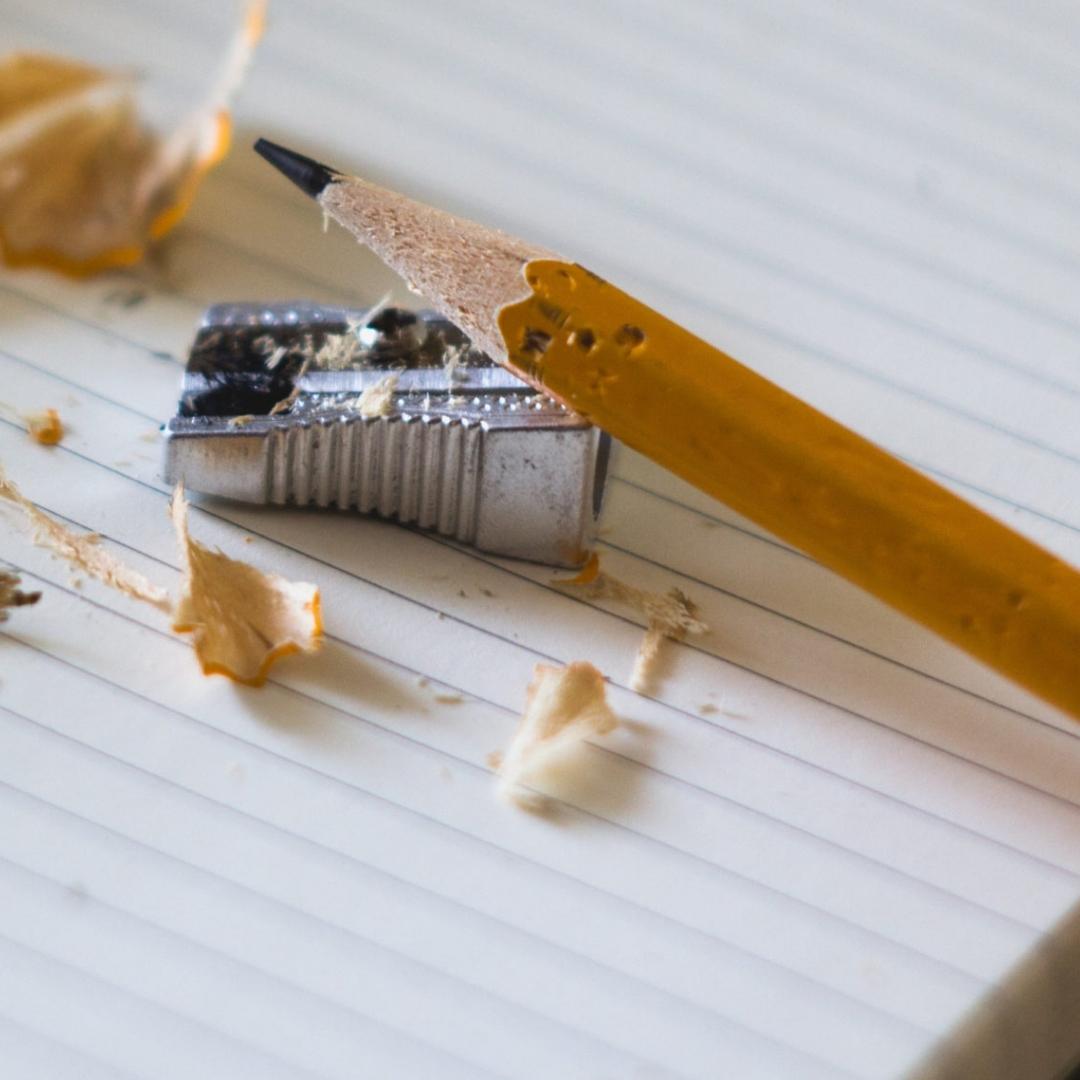 A pencil resting on top of a pencil sharpener on a lined page